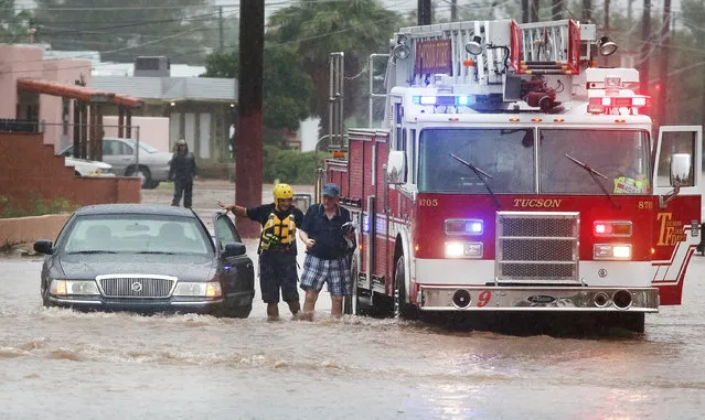 Tucson firefighters with Ladder 9 attend to a stranded motorist as heavy rains flood the intersection of North Country Club Road and East Seneca Street, Tuesday, August 9, 2016, in Tucson, Ariz. Heavy rain associated with Tropical Storm Javier in Mexico fell over the American Southwest. (Photo by Mike Christy/Arizona Daily Star via AP Photo)