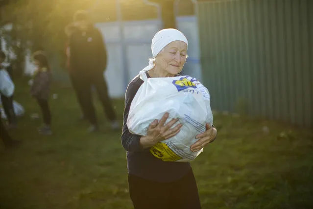 A local woman carries a bag with food given by Ukrainian volunteers in recently retaken Pidlyman village, east Ukraine, Friday, October 7, 2022. (Photo by Francisco Seco/AP Photo)