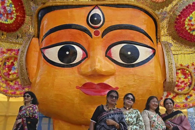 Visitors pose for pictures in front of an art installation next to a Durga Puja pandal in Kolkata on October 4, 2022. (Photo by Dibyangshu Sarkar/AFP Photo)