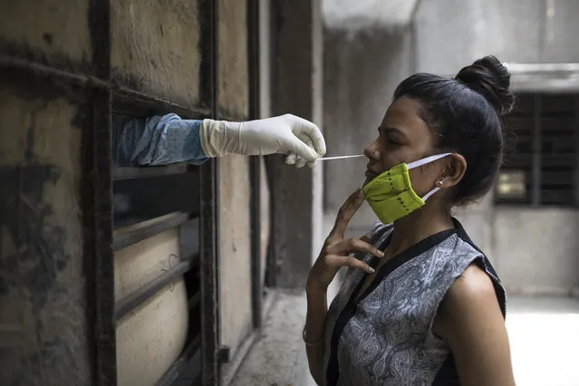 A health official (L) collects a swab sample from a woman to test for the COVID-19 coronavirus at a temporary free testing facility set up in a school after authorities eased restrictions imposed as a preventive measure against the spread of the COVID-19 coronavirus, in New Delhi on June 19, 2020. (Photo by Xavier Galiana/AFP Photo)
