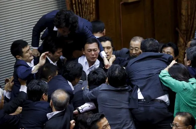 Opposition Democratic Party of Japan lawmaker Hiroyuki Konishi (top) climbs over other lawmakers who are guarding Yoshitada Konoike, chairman of the upper house special committee on security, before a vote at an upper house special committee session on security-related legislation at the parliament in Tokyo, Japan, September 17, 2015. (Photo by Toru Hanai/Reuters)