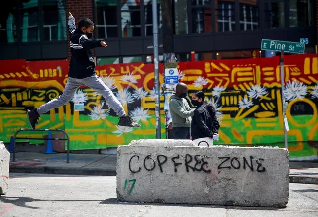 Jamil jumps onto a barricade with graffiti reading “Cop free zone” as his parents stand nearby at the CHOP area as people continue to occupy space and protest against racial inequality in Seattle, Washington, June 28, 2020. (Photo by Lindsey Wasson/Reuters)
