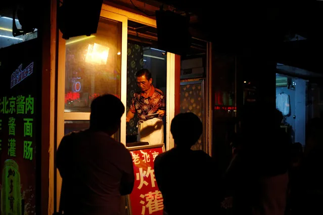 People line up at the window of a food stall in Beijing, China, August 25, 2016. (Photo by Thomas Peter/Reuters)