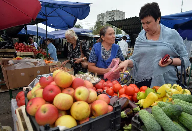A woman (R) buys vegetables at a food market in Moscow on August 12, 2016. (Photo by Natalia Kolesnikova/AFP Photo)