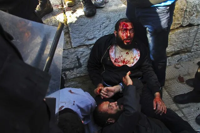 An injured men takes shelter during clashes between supporters and opponents of President Mohammed Morsi in Alexandria, Egypt, December 14, 2012. (Photo by Ahmed Ramadan/Associated Press)