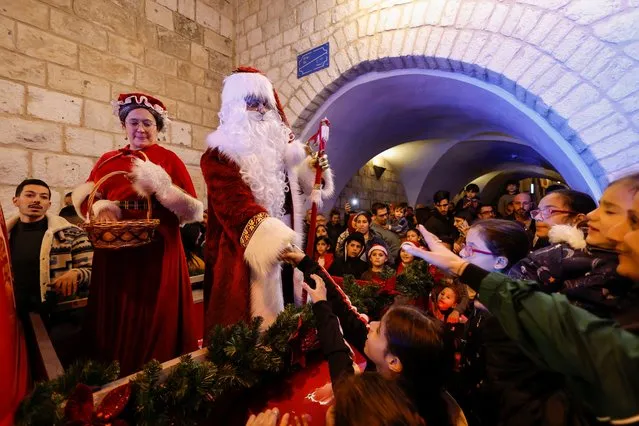 A Palestinian dressed as Santa Claus shakes hands with children during a celebration in Bethlehem, in the Israeli-occupied West Bank on December 4, 2022. (Photo by Mussa Qawasma/Reuters)