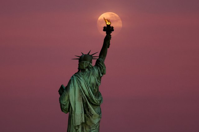 The Flower Moon rises through clouds behind the Statue of Liberty as the sun sets in New York City on May 11, 2025, as seen from Jersey City, New Jersey. (Photo by Gary Hershorn/Getty Images)