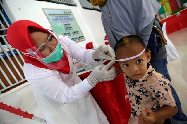 A nurse measures a child during a routine immunization campaign at The Children Community Health Care center in Banda Aceh, Indonesia, 13 August 2020 According to data from the Indonesia Ministry of Health, the children's health service programs decreased dramatically during the start of the coronavirus pandemic. (Photo by Hotli Simanjuntak/EPA/EFE)