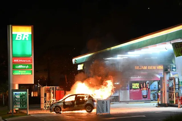 A vehicle burns at a gas station following clashes between riot police and supporters of President Jair Bolsonaro protesting the arrest of an indigenous leader in Brasilia, on December 12, 2022. (Photo by Evaristo Sa/AFP Photo)