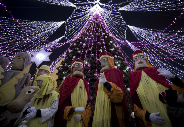 Lithuanians dressed as the Three Kings are seen at the Christmas tree at Cathedral square, during the Epiphany Day celebrations in Vilnius, Lithuania, Saturday, January 6, 2018. Epiphany, the 12th night of Christmas, marks the day the three wise men visited Christ. (Photo by Mindaugas Kulbis/AP Photo)