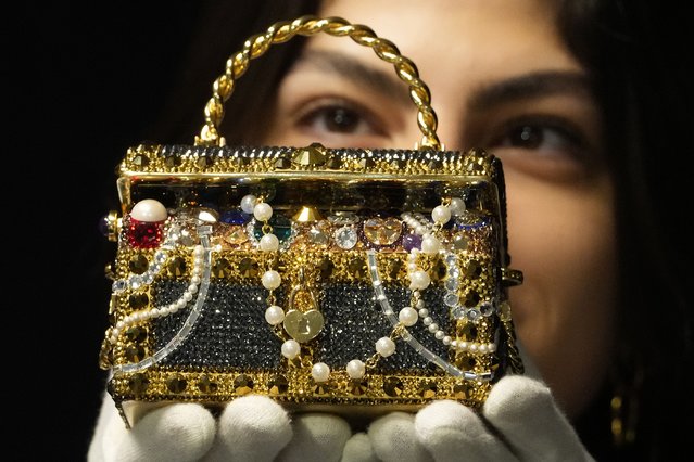 A Bonhams employee displays a Judith Leiber: Gold “Sunken Treasure Chest” Clutch Bag at the auction rooms in London, Monday, February 26, 2024. The bag estimated at 600-800 UK Pounds (760-1015 US Dollars) will be for auction in the live sale on Feb. 28, it will feature luxurious items of handbags and ready-to-wear designs from coveted names including Chanel, Hermes, Karl Lagerfeld for Chanel, Christian Dior, Louis Vuitton, and Gucci. (Photo by Kirsty Wigglesworth/AP Photo)