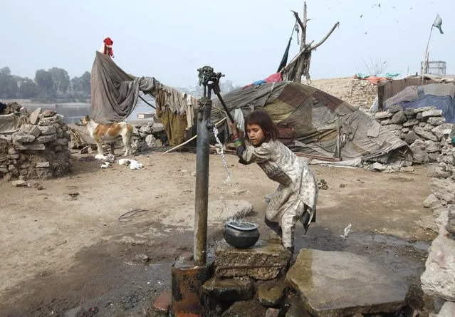 A girl uses a water pump to fill her pot on the outskirts of Lahore, Pakistan, on February 1, 2013. (Photo by Mohsin Raza/Reuters)