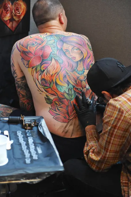 A tattooist at work at the the 12th London International Tattoo Convention, which opened today in Tobacco Dock, east London on September 23, 2016. (Photo by Michael Preston/Alamy Live News)
