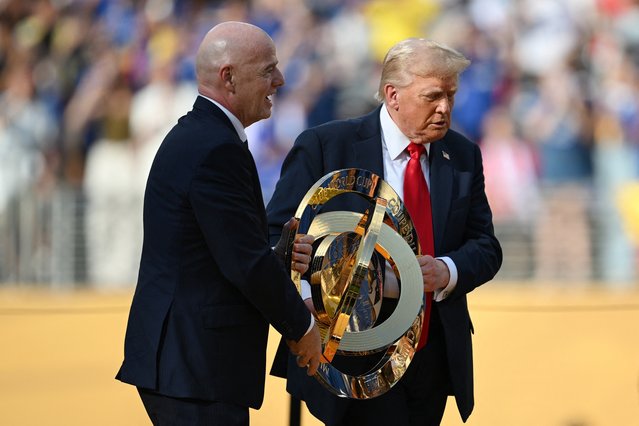 FIFA President Gianni Infantino (L) and US President Donald Trump carry the trophy during the award ceremony for the FIFA Club World Cup 2025 Champions, following the final football match between England's Chelsea and France's Paris Saint-Germain at the MetLife Stadium in East Rutherford, New Jersey on July 13, 2025. (Photo by Angela Weiss/AFP Photo)