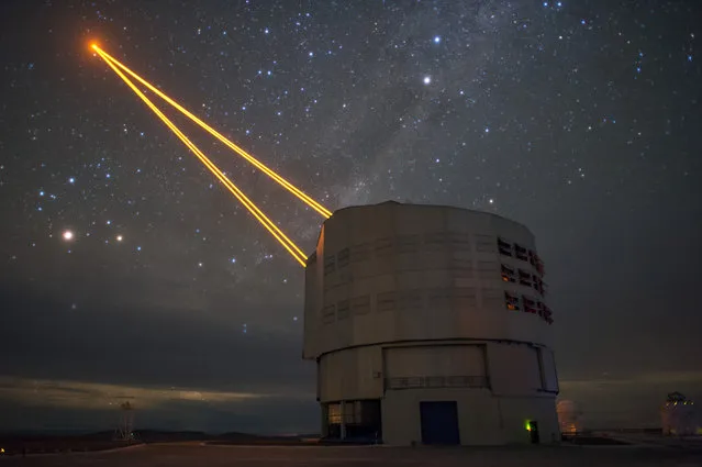Four lasers reach into the night sky at the European Southern Observatory's Very Large Telescope on September 2, 2016 in Paranal, Chile. The lasers are a part of the adaptive optics system on the VLT which allows astronomers to drastically reduce the atmospheric distortion present at even the best sites in the world for astronomy. (Photo by F. Kamphues/ESO)