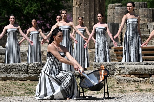 Greek actress Mary Mina, playing the role of the High Priestess, lights the torch during the rehearsal of the flame lighting ceremony for the Paris 2024 Olympics Games at the ancient temple of Hera on the Olympia archeological site, birthplace of the ancient Olympics in southern Greece, on April 15, 2024. (Photo by Aris Messinis/AFP Photo)