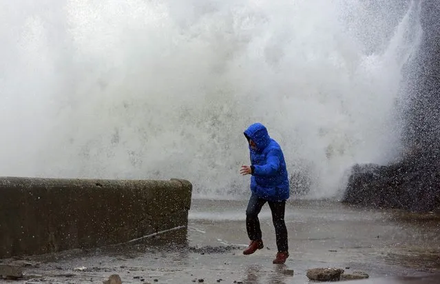 A man runs as waves crash against the harbour wall at Portstewart in northern Ireland December 10, 2014. (Photo by Cathal McNaughton/Reuters)