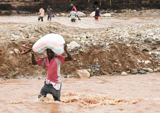 A man wades through a flooded river caused by last week's heavy rains caused by Tropical Cyclone Freddy in Phalombe, southern Malawi Saturday, March 18, 2023. (Photo by Thoko Chikondi/AP Photo)