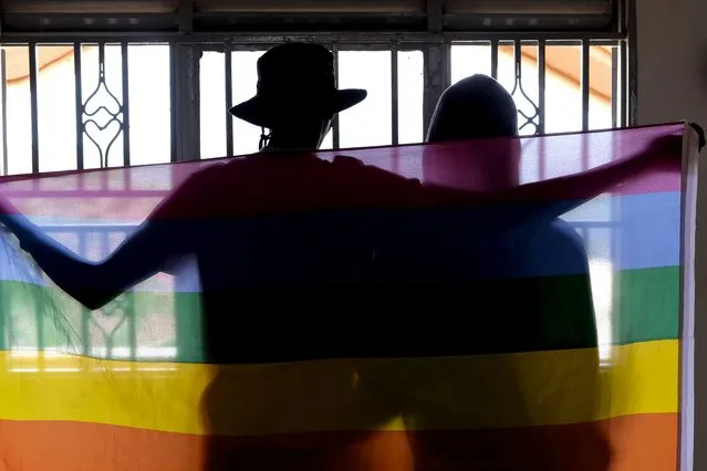 A gay Ugandan couple cover themselves with a pride flag as they pose for a photograph in Uganda Saturday, March 25, 2023. A prominent leader of Uganda's LGBTQ community on Thursday described anguished calls by others like him who are concerned for their safety after the passing of a harsh new anti-gay bill. (Photo by AP Photo/Stringer)