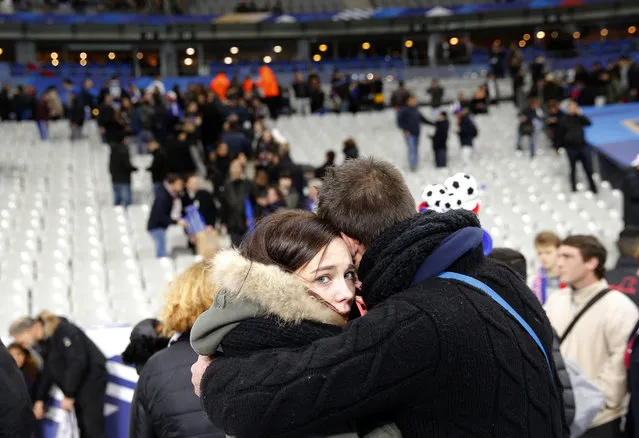 A supporter conforts a friend after invading the pitch of the Stade de France stadium at the end of the international friendly soccer match between France and Germany in Saint Denis, outside Paris, Friday, November 13, 2015. Hundreds of people spilled onto the field of the Stade de France stadium after explosions were heard nearby. (Photo by Christophe Ena/AP Photo)