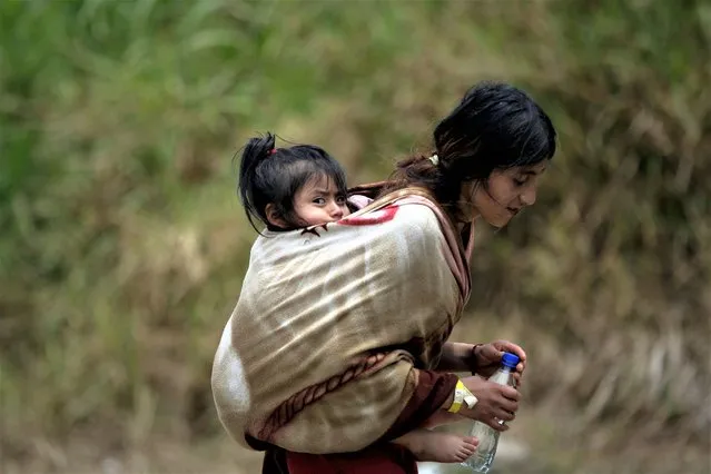 An Ecuadorian migrant carries her daughter through the jungle while they wait to be transferred by canoe from Quebrada Leon to the community of Bajo Chiquito, in Darien, Panama, 10 March 2023. (Photo by Bienvenido Velasco/EPA/EFE)