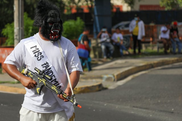 A person holds a toy rifle in front of a banner during a demonstration to commemorate the 49th Anniversary of the Student Massacre that occurred on July 30, 1975, in San Salvador, El Salvador on July 30, 2024. The university students claim that 49 years ago the army and members of the National Guard of El Salvador stopped a student march with an armed attack that remains unpunished. And the current Salvadoran government does not clarify the case, and also increases the economic debt for the university budget. (Photo by Alex Pena/Anadolu via Getty Images)