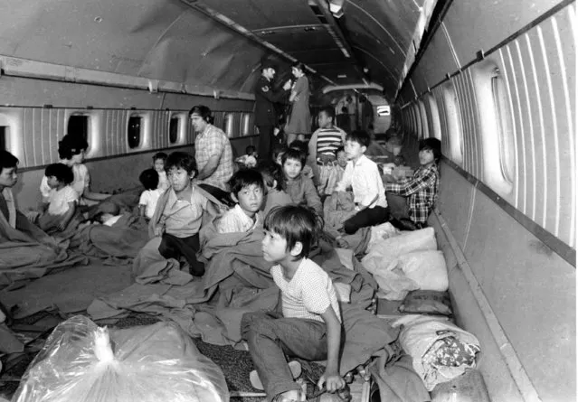 Vietnamese orphans, some wrapped in blankets, sit on the floor of a World Airway DC8 jet as the plane stopped over at Yokata U.S. Air Force Base in northewestern Tokyo, during the Vietnam War, April 3, 1975. The children are the first South Vietnam refugees evacuated aboard an American airliner. (Photo by AP Photo)