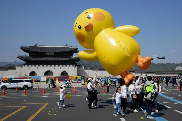 Participants carrying a character balloon march near the Gwanghwamun, one of South Korea's well-known landmarks, during the Easter parade in Seoul, South Korea, Sunday, April 9, 2023. (Photo by Lee Jin-man/AP Photo)