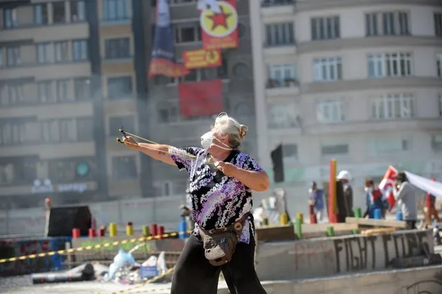 A protestors uses a slingshot against Turkish riot police on Taksim square on June 11, 2013. Riot police fired tear gas and rubber bullets to clear protesters from an Istanbul square on June 11 as Turkish Prime Minister Recep Tayyip Erdogan warned he would show “no more tolerance” for the unrelenting mass demonstrations against his Islamic-rooted government. Hundreds of police stormed the city's Taksim Square, the epicenter of nearly two weeks of unrest, in the early morning and brought bulldozers to clear the makeshift barriers erected by demonstrators after police pulled out of the area on June 1. (Photo by Bulent Kilic/AFP Photo)