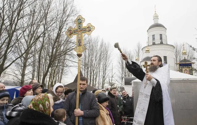 An Orthodox priest leads a service on the eve of Epiphany in Minsk, January 18, 2015.   Orthodox believers mark Epiphany, which falls on January 19, by immersing themselves in icy waters regardless of the weather. (Photo by Vasily Fedosenko/Reuters)