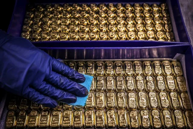 A worker polishes gold bullion bars at the ABC Refinery in Sydney on August 5, 2020. Gold prices hit 2,000 USD an ounce on markets for the first time on August 4, the latest surge in a commodity seen as a refuge amid economic uncertainty. (Photo by David Gray/AFP Photo)