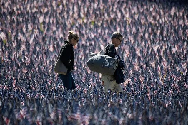 People tour a memorial with US flags set next to the Soldiers and Sailors Monument by the Massachusetts Military Heroes Fund for Memorial Day, in Boston, Massachusetts, on May 26, 2023. More than 37,000 US flags were planted around the monument in Boston Common to honor each US military member from the state who died while serving since the Revolutionary War. (Photo by Joseph Prezioso/AFP Photo)