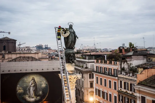 A firefighter places a wreath on the statue of the Immaculate Conception in Rome, Italy on December 8, 2015. (Photo by Rex/Shutterstock)