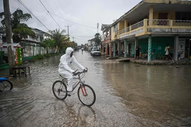 A man rides his bicycle through a flooded neighborhood in Les Cayes, Haiti on May 30, 2023. (Photo by Richard Pierrin/AFP Photo)