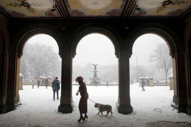 A woman walks a dog through the Bethesda Terrace in Central Park as heavy snow falls in Manhattan, New York City, U.S., February 7, 2021. (Photo by Andrew Kelly/Reuters)