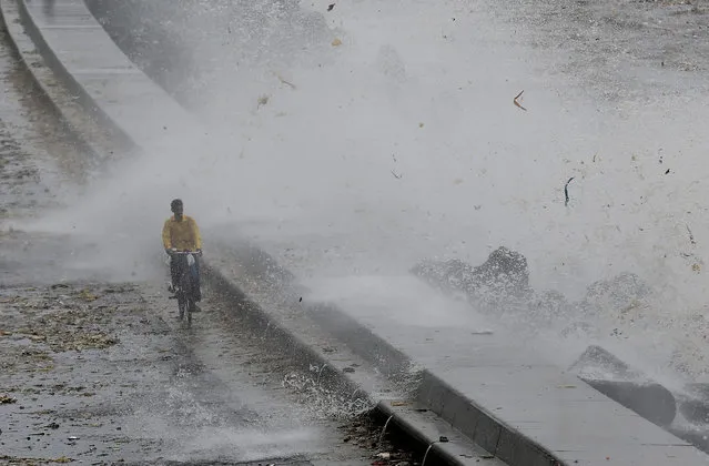 A man rides his bicycle as a wave crashes during high tide at a sea front in Mumbai, India, July 13, 2018. (Photo by Francis Mascarenhas/Reuters)