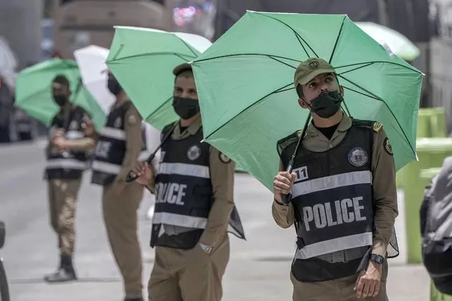 Saudi policemen hold their umbrellas at the Mina tent camp, in Mecca, Saudi Arabia, during the annual hajj pilgrimage, Monday, June 26, 2023. Muslim pilgrims are converging on Saudi Arabia's holy city of Mecca for the largest hajj since the coronavirus pandemic severely curtailed access to one of Islam's five pillars. (Photo by Amr Nabil/AP Photo)