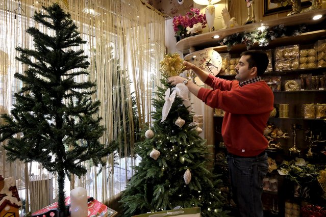 A shopkeeper sets up a Christmas tree at a shop in central Tehran December 23, 2015. (Photo by Raheb Homavandi/Reuters)
