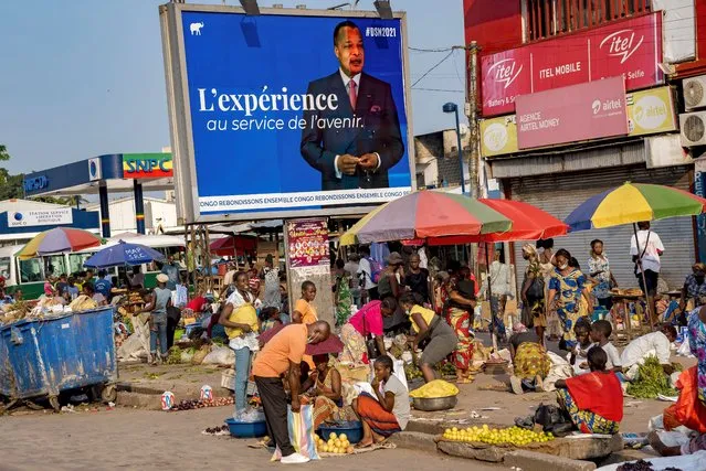 An election poster featuring President Denis Sassou N'Guesso stands over a market in central Brazzaville, Congo, Sunday March 7, 2021. Elections on Sunday March 21 will see President Denis Sassou N'Guesso poised to extend his tenure as one of Africa's longest serving leaders, 36 years, amid opposition complaints of interference with their campaigns. (Photo by Lebon Chansard Ziavoula/AP Photo)