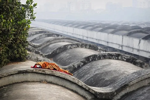 A homeless person sleeps on the roof of a railway station in Dhaka on March 22, 2021. (Photo by Munir Uz Zaman/AFP Photo)