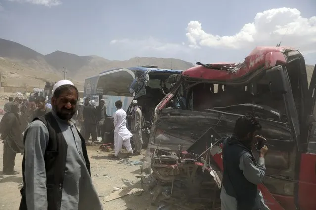 Afghan men stand near damaged buses after a deadly accident on the Kabul-Kandahar highway, on the outskirts of Kabul, Afghanistan, Tuesday, April 27, 2021. Two buses crashed head-on killing several people and injuring more than 70, an Afghan official said Tuesday. (Photo by Rahmat Gul/AP Photo)