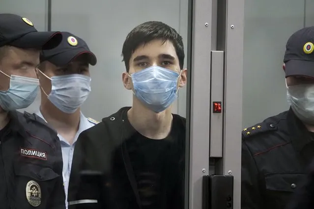 Ilnaz Galyaviyev,  centre,wearing a face mask to protect against coronavirus, stands behind a glass, surrounded by police officers during a hearing in a courtroom in Kazan, Russia, Wednesday, May 12, 2021. Russian officials say Galyaviyev attacked a school in the city of Kazan and Russian officials say several people have been killed. Russian media said the gunman was a former student at the school who called himself “a god” on his account on the messaging app Telegram and promised to “kill a large amount of biomass” on the morning of the shooting. Authorities also say over 20 others have been hospitalised with wounds. (Photo by Dmitri Lovetsky/AP Photo)