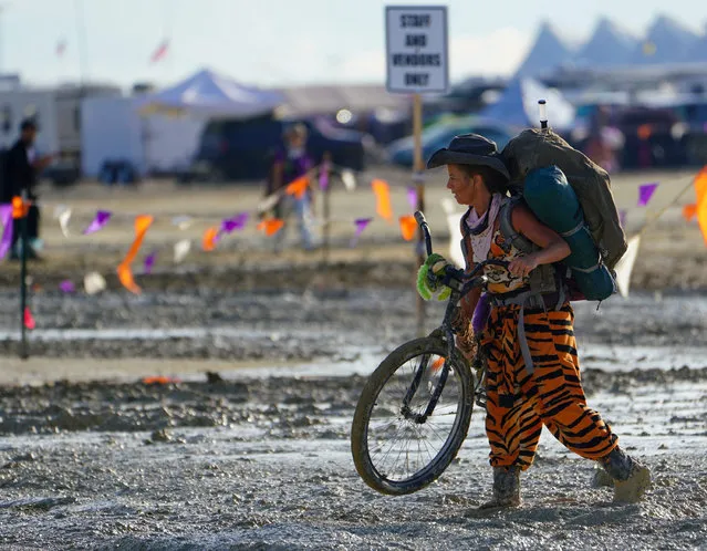 A Burning Man participant walks their bike through the mud near the exit, after a severe rainstorm left tens of thousands of revelers attending the annual festival stranded in mud in Black Rock City, in the Nevada desert on September 3, 2023. (Photo by Trevor Hughes/USA Today Network via Reuters)