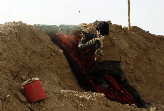 A Shi'ite fighter fires his weapon during clashes with Islamic State militants in Salahuddin province March 2, 2015. Iraq's armed forces, backed by Shi'ite militia, attacked Islamic State strongholds north of Baghdad on Monday as they launched an offensive to retake the city of Tikrit and the surrounding Sunni Muslim province of Salahuddin.  REUTERS/Thaier Al-Sudani 