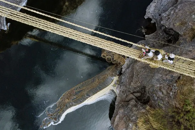 Aerial view showing people from different communities participating in the annual renovation of the Q'eswachaka rope bridge, as the old one drifts away in the Apurimac river, near Huinchiri, Quehue District, Cusco Department, in southern Peru, on June 9, 2023. The Q'eswachaka hand-woven straw bridge, which hangs over the Apurimac river, is rebuilt by local indigenous communities every June in a ritual that lasts three days. (Photo by Christian Sierra/AFP Photo)
