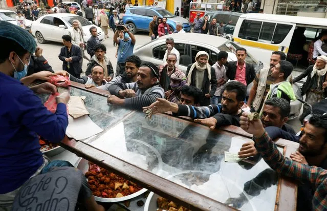People gather outside a pastry shop to buy sambusa during the holy month of Ramadan in Sanaa, Yemen on April 15, 2021. (Photo by Khaled Abdullah/Reuters)