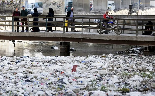 People walk across a bridge surrounded by litter and waste at a canal connected to the river Nile in Cairo March 22, 2015. (Photo by Amr Abdallah Dalsh/Reuters)