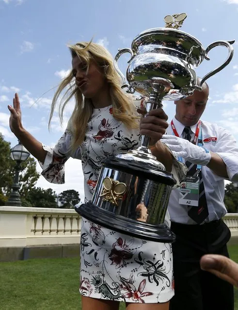 Germany's Angelique Kerber reacts holding the women's singles trophy while a security guard assists her after her shoe was stuck, a day following her win in the final match at the Australian Open tennis tournament, at the Government House in Melbourne, Australia, January 31, 2016. (Photo by Issei Kato/Reuters)