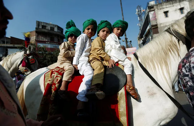 Muslim boys sit on a horse during a religious procession to mark Eid-e-Milad-ul-Nabi, or birthday celebrations of Prophet Mohammad, in the old quarters of Delhi, November 21, 2018. (Photo by Adnan Abidi/Reuters)