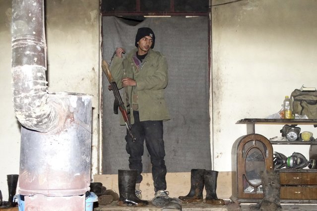 A rebel fighter carries his weapon in a safe house in the northwestern Homs district of Al Waer January 18, 2015. (Photo by Reuters/Stringer)